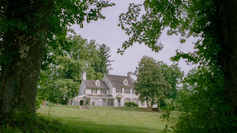 A large white house surrounded by trees and grass