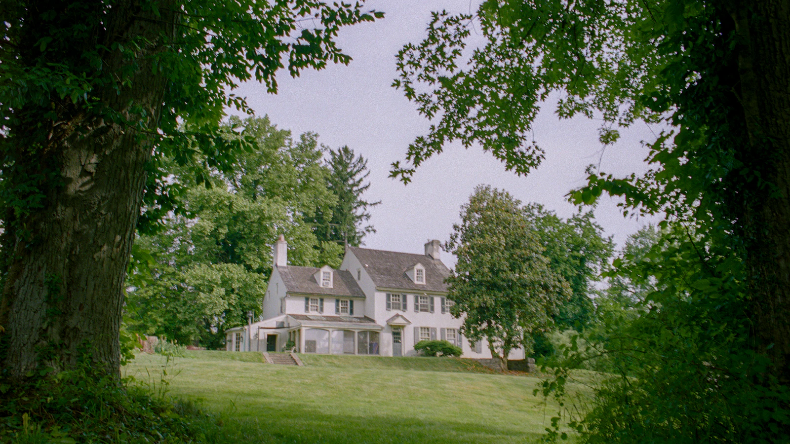 A large white house surrounded by trees and grass