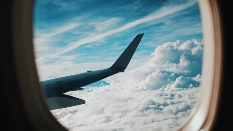 An airplane wing seen through the window above the clouds