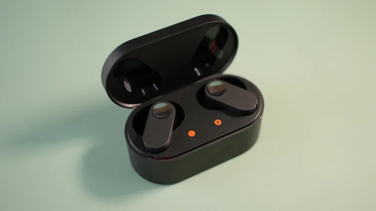 Wireless earbuds resting beside an open charging case