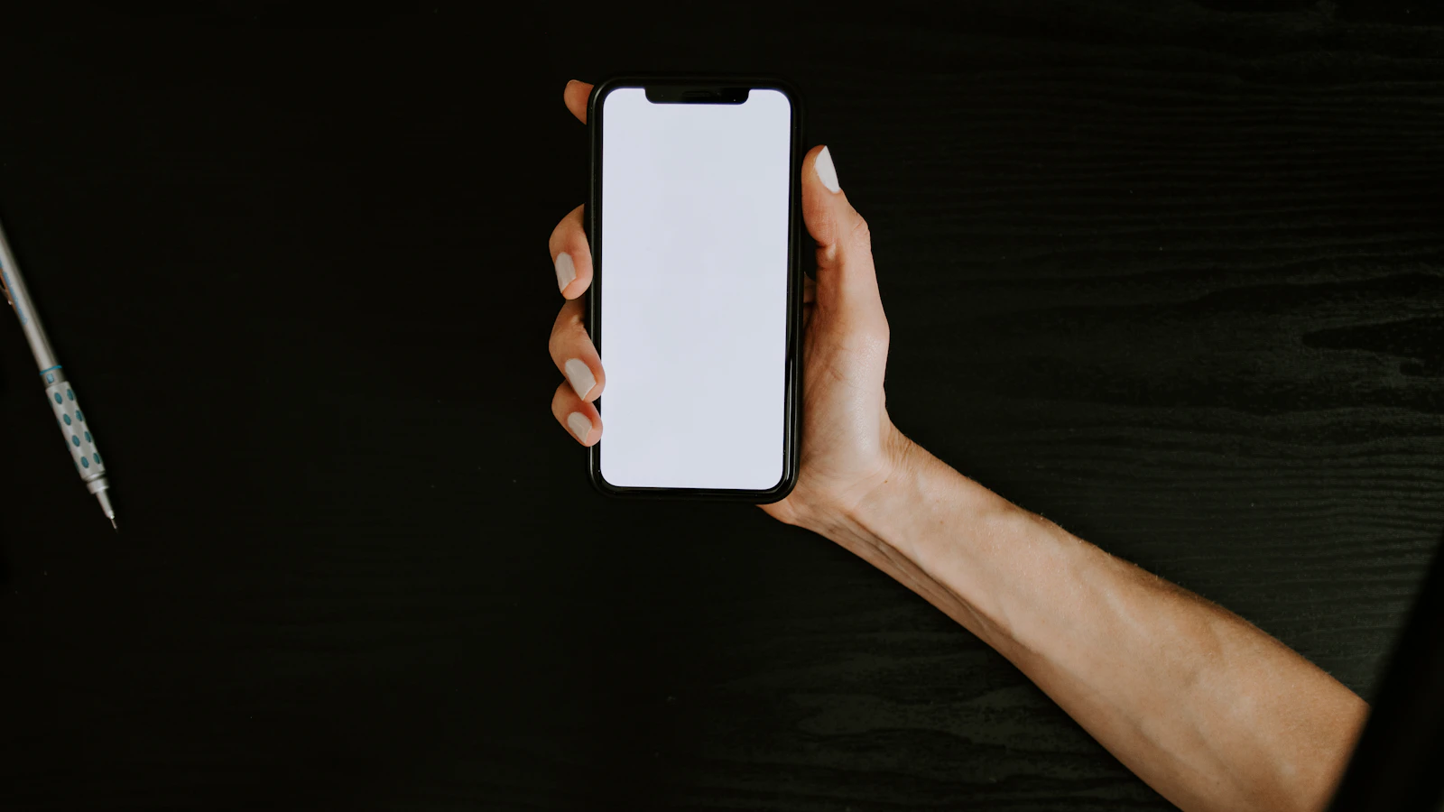 A hand holding a smartphone ready for charging