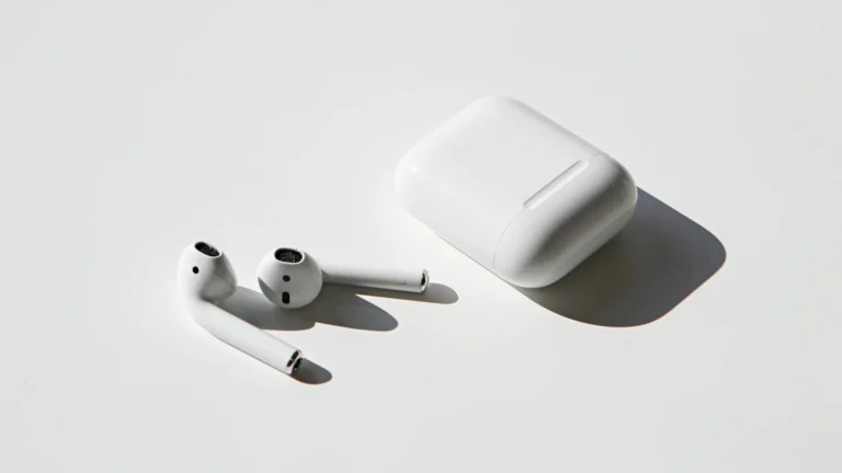 Wireless earbuds on a white table beside their case