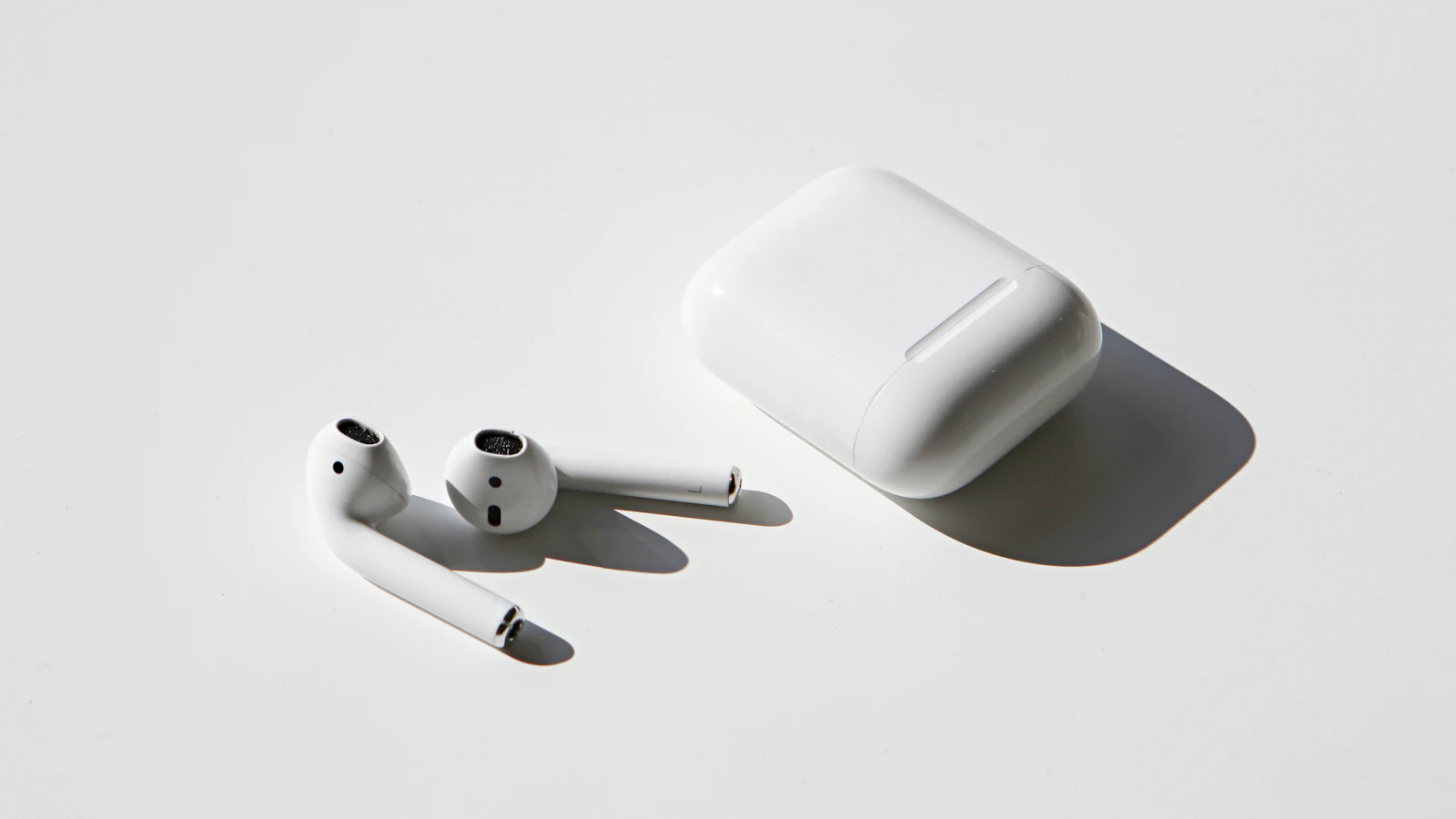 Wireless earbuds on a white table beside their case